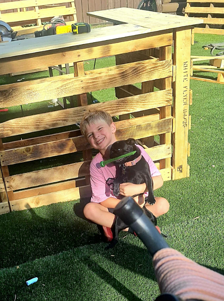 Jaxon Lupton, 6, of Coeur d'Alene, and furry friend Shadow take a break from building a lemonade stand in preparation for Lemonade Day Kootenai County, coming up Saturday.