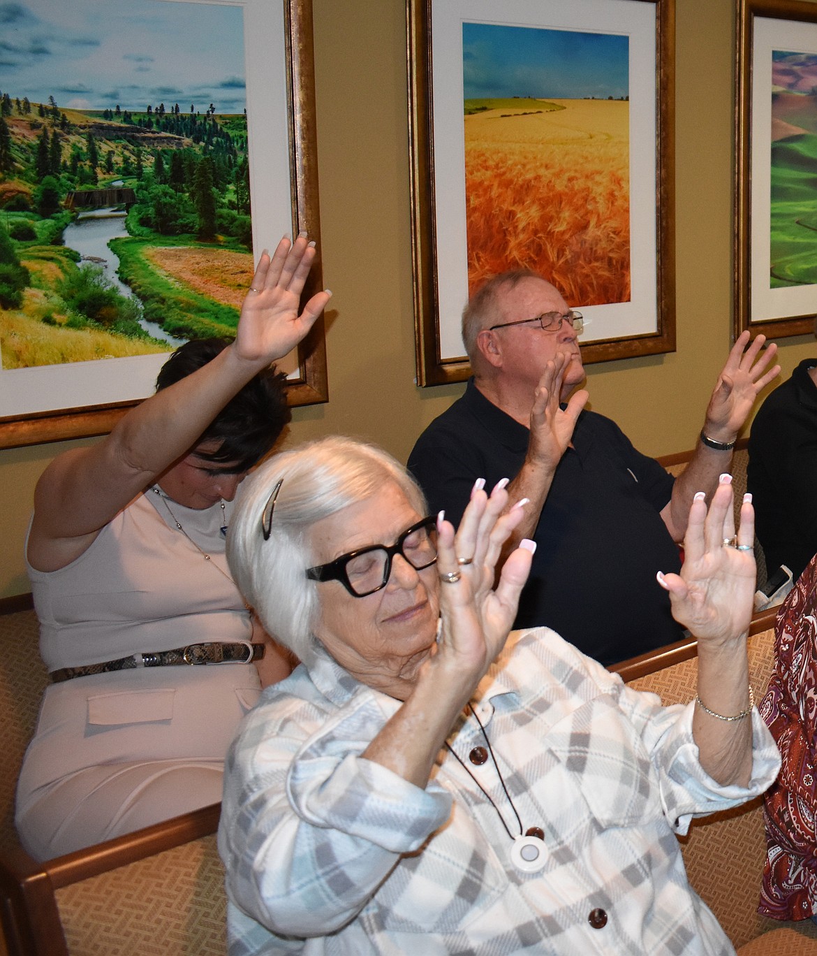 Visitors, resident sand staff raise their hands to join in blessing the chapel at Brookdale Hearthstone Thursday. About 15-20 people were present as well as representatives from three local churches.