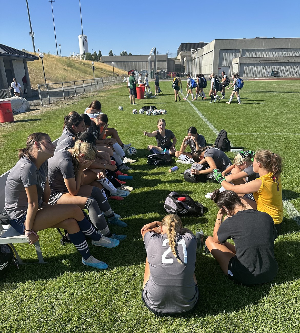 The Mavs girls soccer team sits around the bench on the sideline during the EWU training camp. The camp featured training sessions from soccer coaches from EWU and scrimmages against schools from a variety of levels.