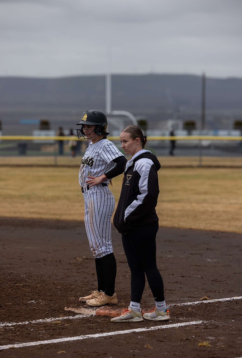 Allison Stanley, a former assistant coach for the Knights, talks with a player at first base. Stanley said she learned a lot watching the game from a coach's perspective rather than a player.