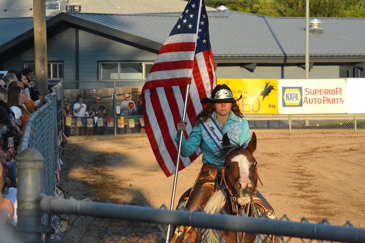 Ranier Acker presented the stars and stripes around the arena as Brynley Conrow sang the national anthem. (Mineral Independent/Amy Quinlivan)