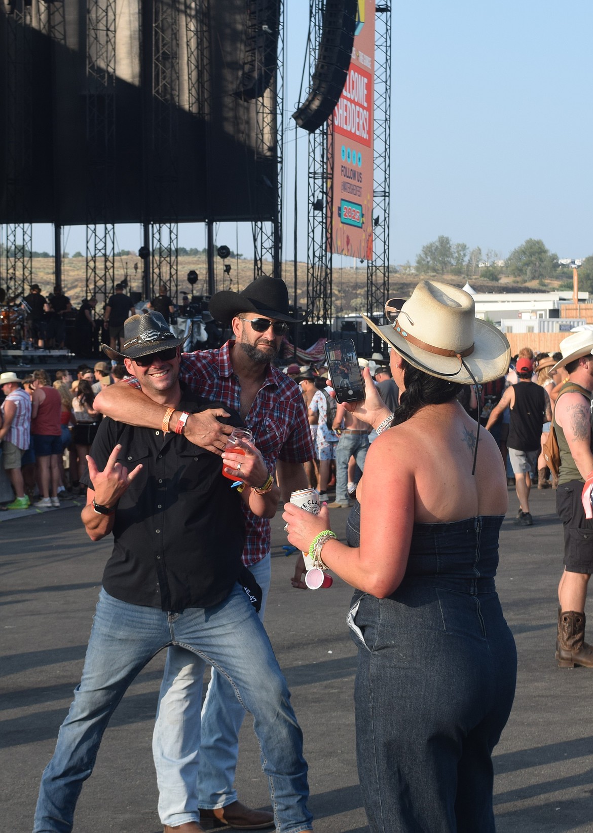 A concertgoer takes a photo of her friends at the main stage of Watershed Festival Saturday.
