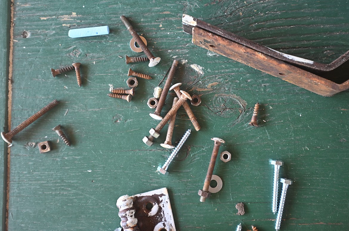 Hinges and screws removed during repairs to Northwest Peak Lookout are scattered across a table. (Hailey Smalley/Daily Inter Lake)