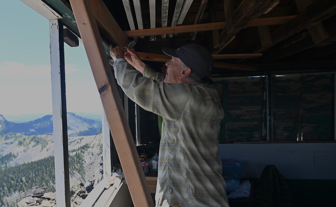 Peter Kitts uses a spare two-by-four to reinforce a crossbeam on the Northwest Peak Lookout. (Hailey Smalley/Daily Inter Lake)