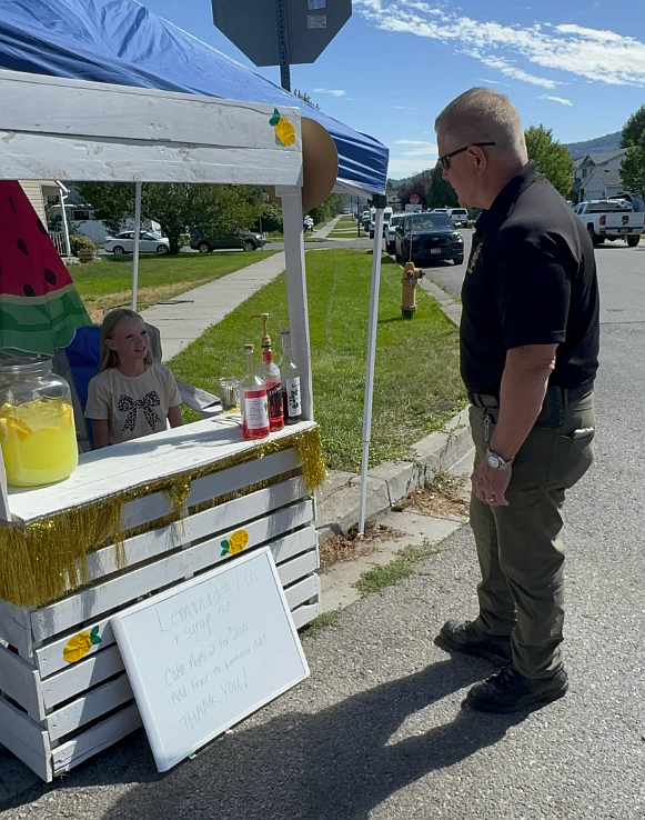 Aspen Pratt, 12, of Post Falls, chats with Kootenai County Sheriff Bob Norris as she sells lemonade July 26 for Make-A-Wish Idaho.