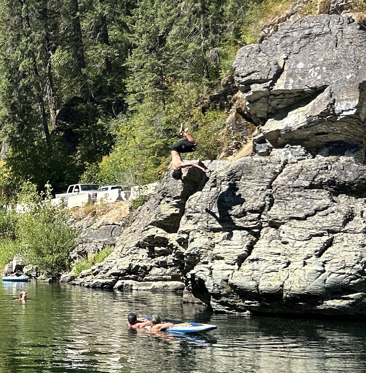 People watch as a person leaps off a rock and heads for a splash landing in the Coeur d'Alene River on Sunday.