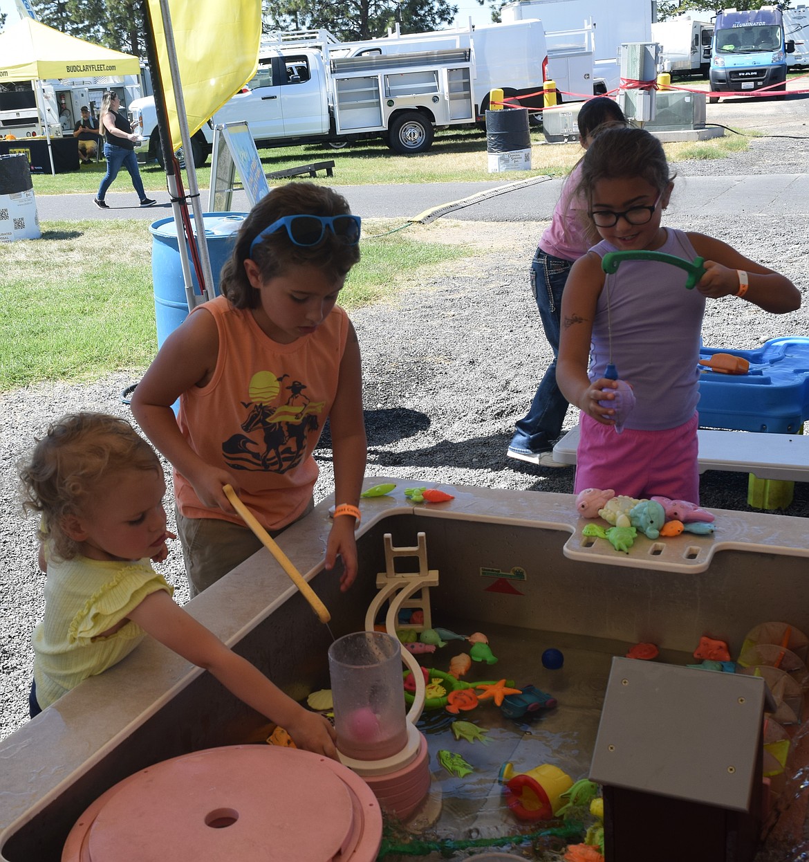 Three young fair attendees work on their fishing skills at the Peppy’s Water Palooza at the Grant County Fair. The station is free and has opportunities for children to play with toys in water and cool down.