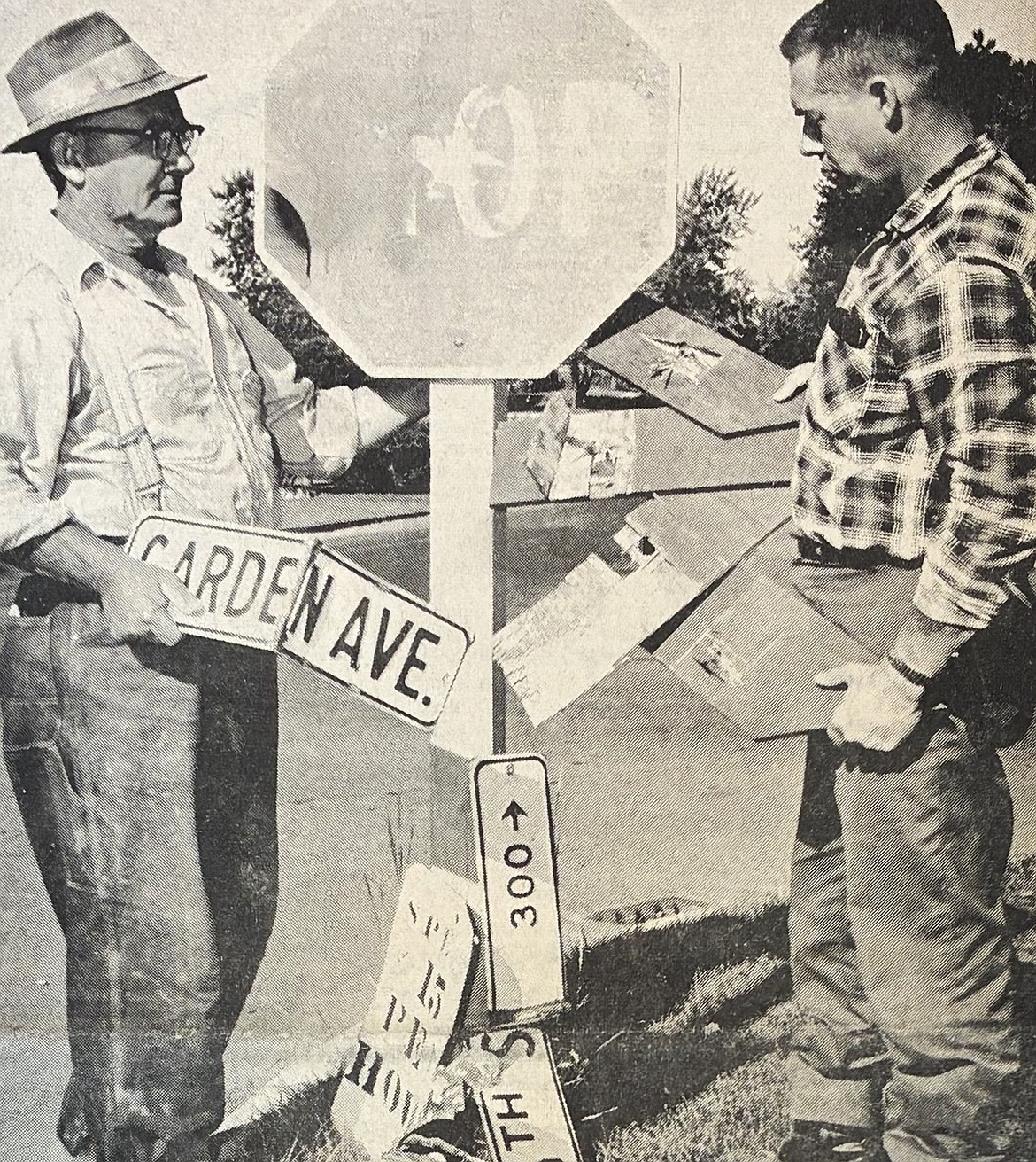 Superintendent Reed Walker of the city streets department and sign maker Carl Erickson survey vandalism at 11th and Garden in 1965.