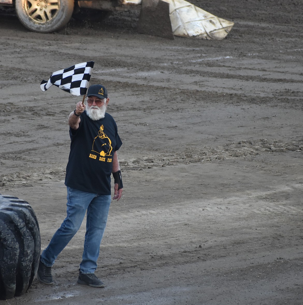 Vern Hellewell waves the checkered flag during the first Heat Race to kick off day two of the demo derby. Hellewell was also just prior to this event honored as the first inductee into the Moses Lake Demo Derby Hall of Fame.