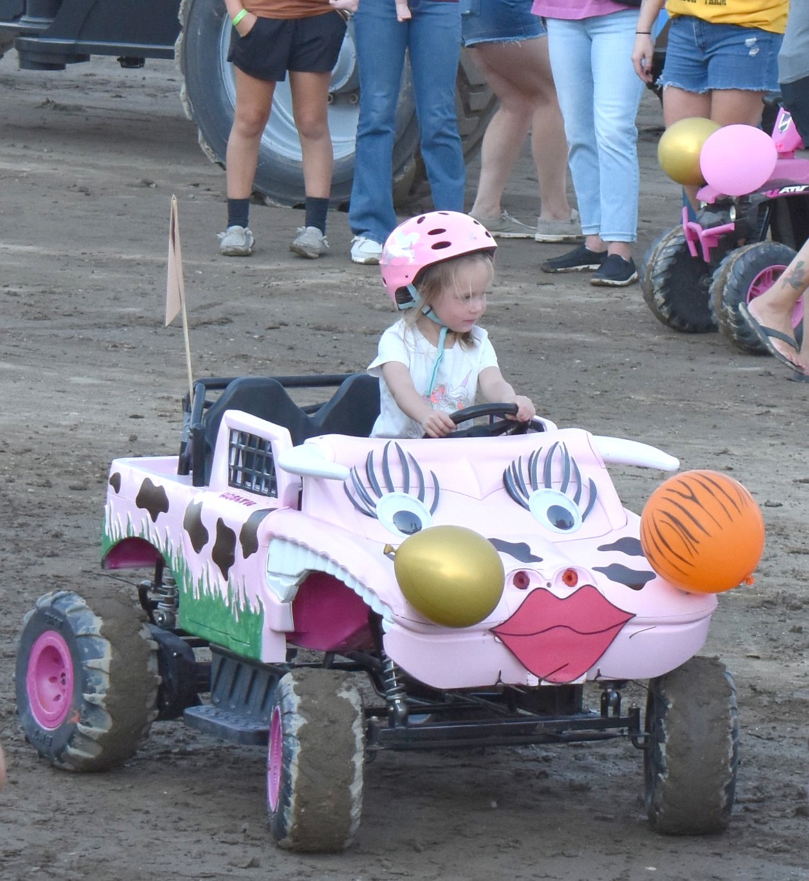 A young girl watches some of the other demo drivers from her decorated pink Power Wheels.