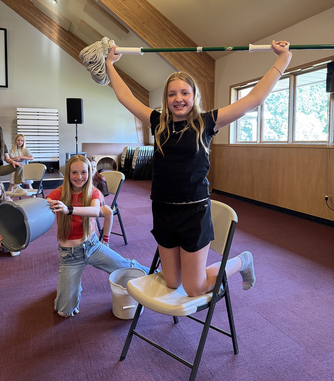 Kylie Anderson hoists a mop above her head alongside castmates Olivia Sherry and
Scarlett Sherry during an "Annie" rehearsal.