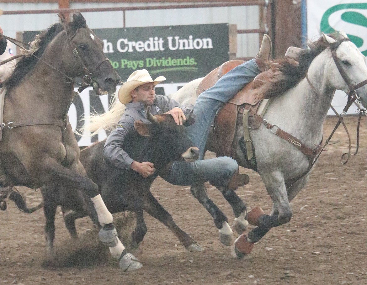 BULLDOGGING Traver Johnson looks to wrestle down a steer during action at the Sanders County fair rodeo Thursday in Plains. (John Hamilton/VP-MI)