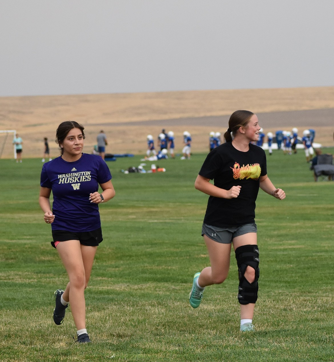 Two players from the Warden soccer team run side by side during their warmup jog around the field before practice. Coach Barbara Landeros said that strengthening their cardio through conditioning.