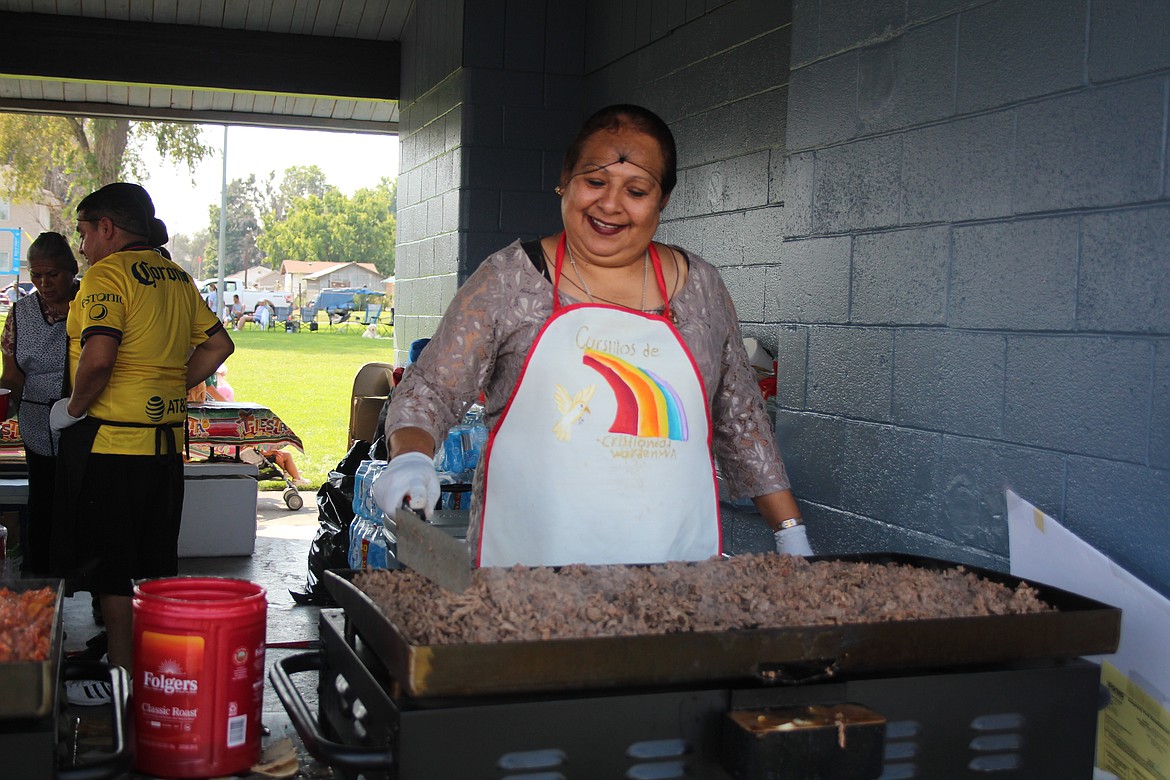 Volunteer Maria Villalobos Lopez tends to one of the grills in the Queen of All Saints Catholic Church booth at Warden Community Days.
