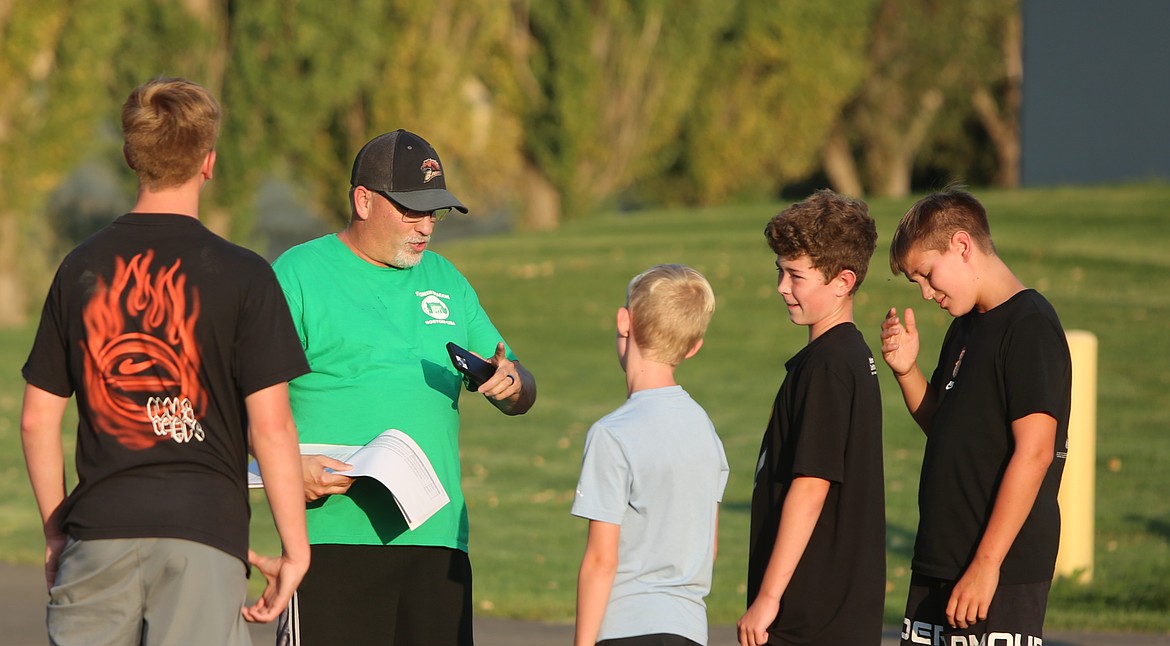 Assistant cross country coach Bryce Court, green, gives feedback to runners during practice. Court is also the Broncos golf coach but has stepped in to help Head Coach Christina Heater this season.