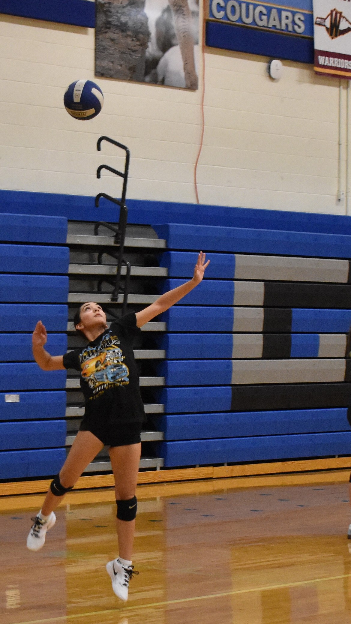 A Cougar player leaps into the air as she serves the ball during warmups at practice. The Cougars have made the state tournament the past two years and are working to return to the tournament again this year.