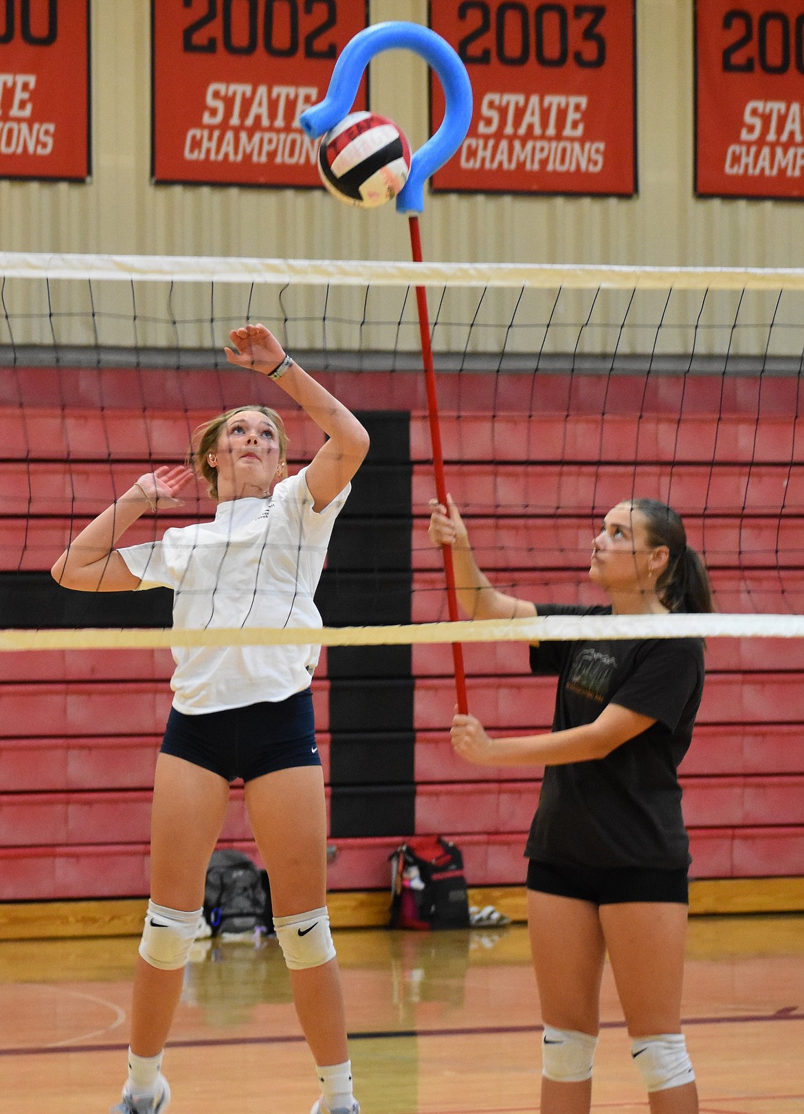 Shaylee Freeman jumps up to hit the ball while Alexa Peterson holds the ball in place with a hook. Freeman said last season was her first year on varsity and has since learned about what she needs to work on to improve her skills.