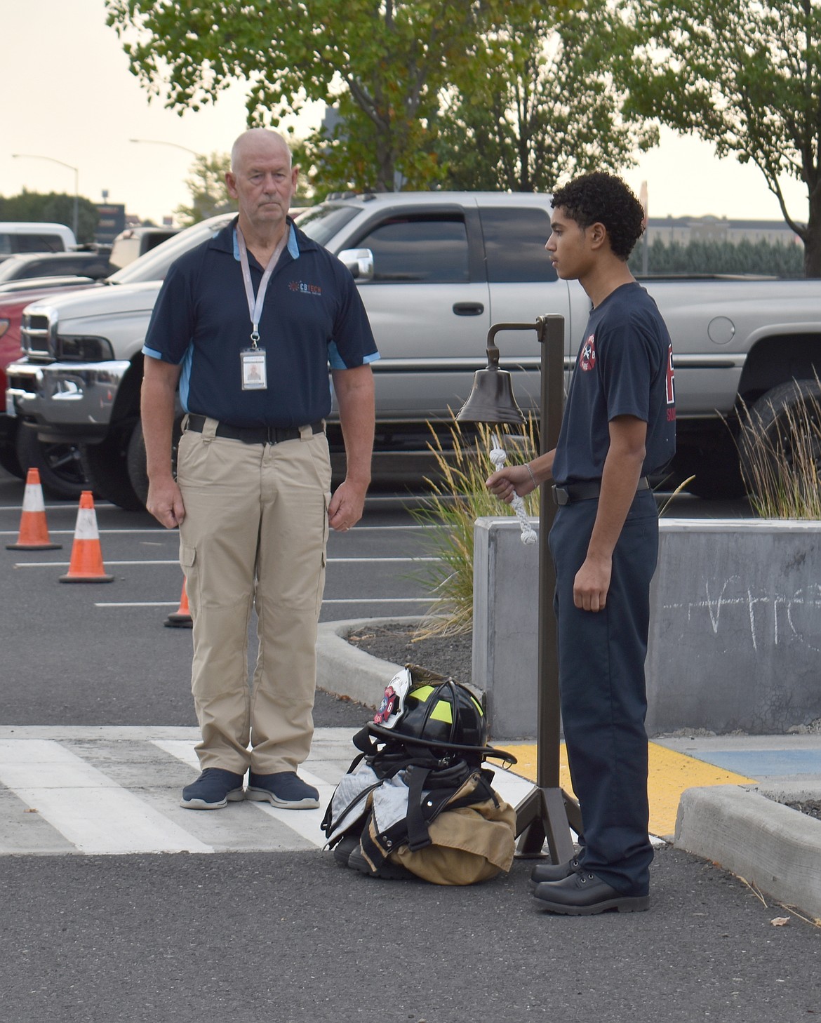 Columbia Basin Technical Skills Center Fire Services student Jeremiah Vargas, right, solemnly rings the Four Fives as law Enforcement instructor Dave Ruffin looks on.