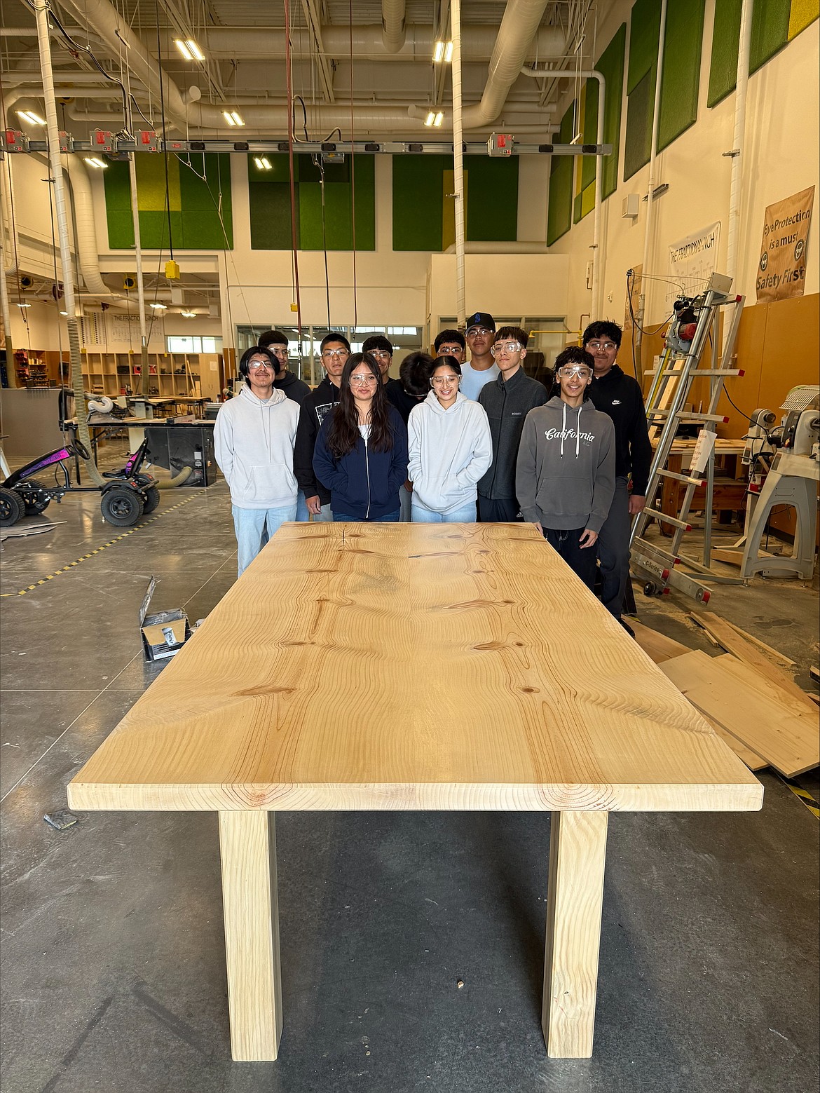 Students in Quincy High School’s advanced construction class show off their handiwork, a table built from the pine trees that once grew outside the Quincy Valley Medical Center.