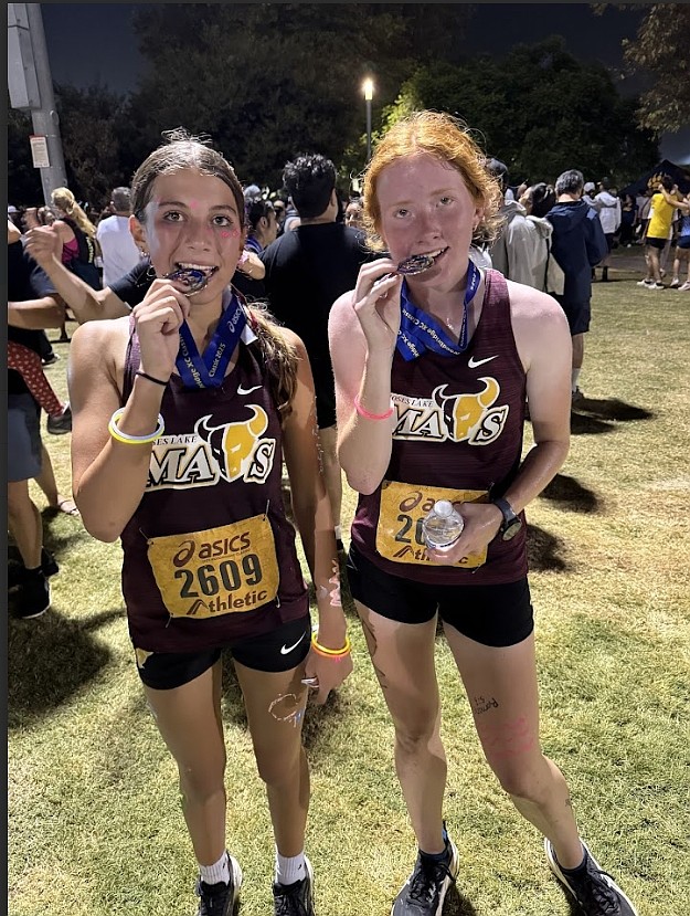 The Mavs’ Aspen Hoenes, left, and Rachel Nofziger, right, celebrate with the medals they earned at the Woodbridge Invitational. Along with Natalie Vehrs and Sara Humpherys, not pictured, they earned their medals for placing in the top 100 of individual runners for girls in their respective races.