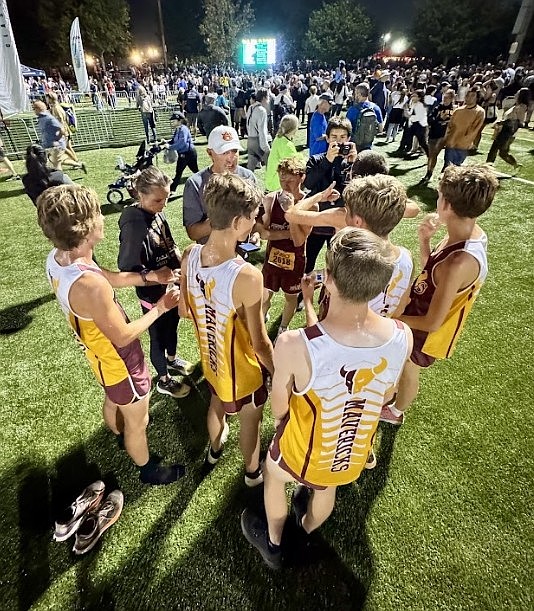 The Mavericks boys team huddles around Head Coach Larry Dagnon at the Woodbridge Invitational. Dagnon called the race a championship atmosphere like they have never seen.