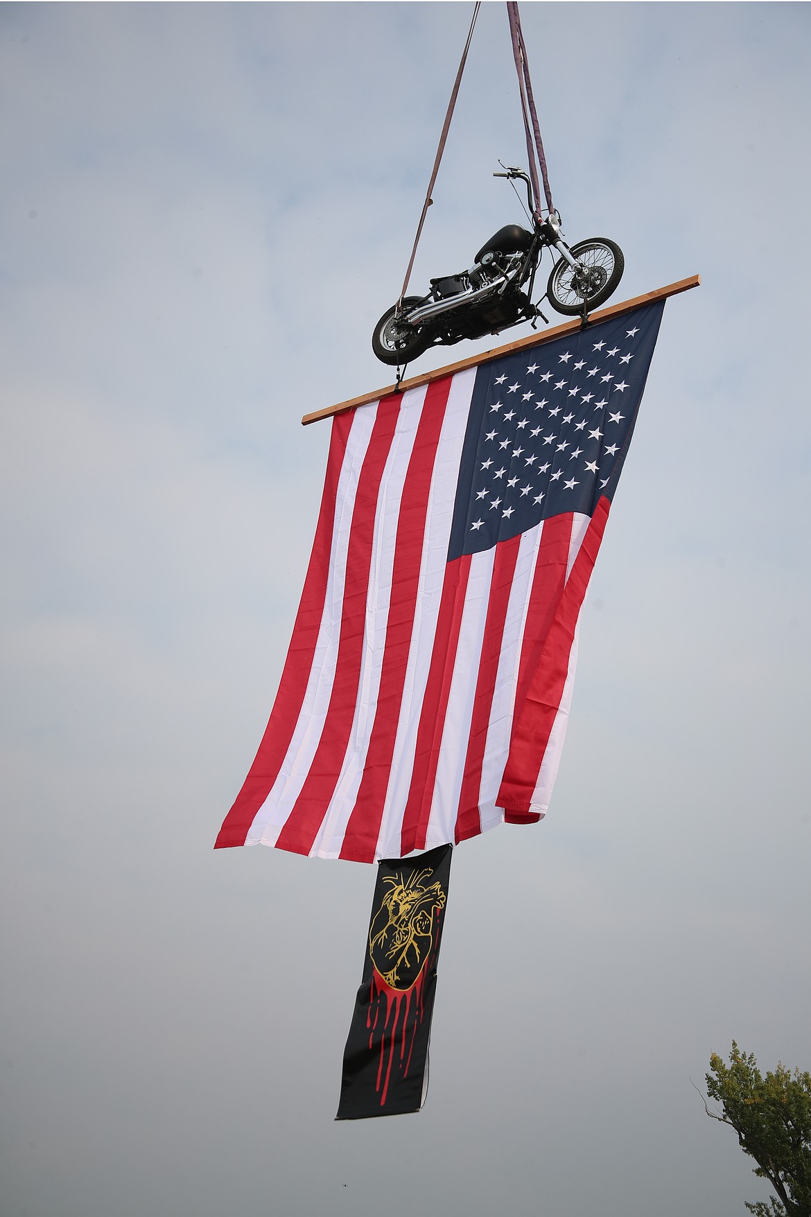 A motorcycle hangs from a crane in tribute to Jose Gomez, the owner of Gription Tire and North Idaho Towing, thanks to friend Jonathan Bates of Bleeding Hearts Tattoo Emporium.
