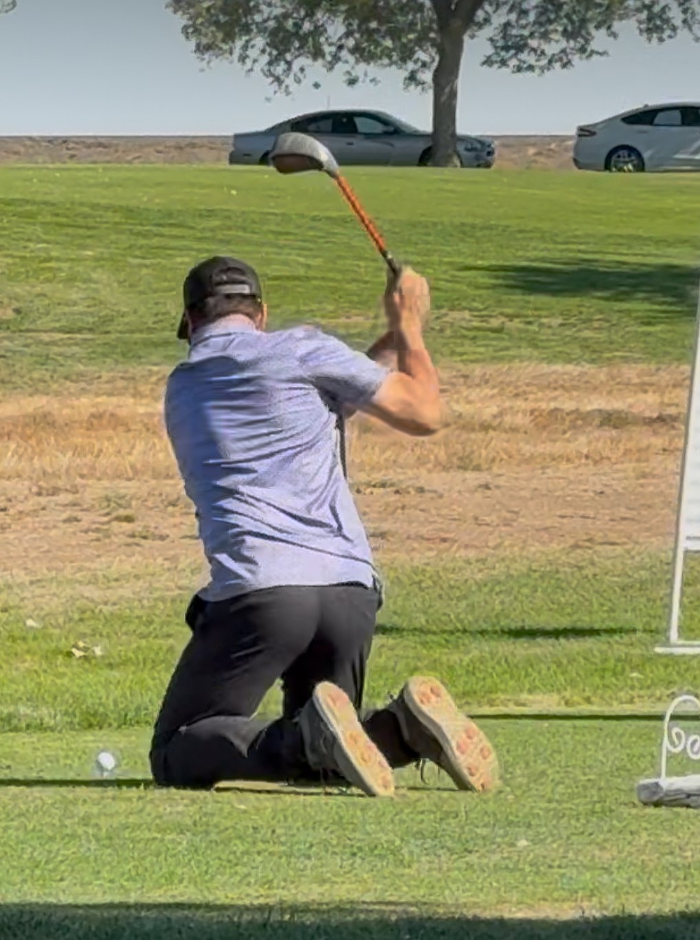 A golfer at the “Dude! Where’s my Cart!?” charity golf tournament tees off while on his knees.