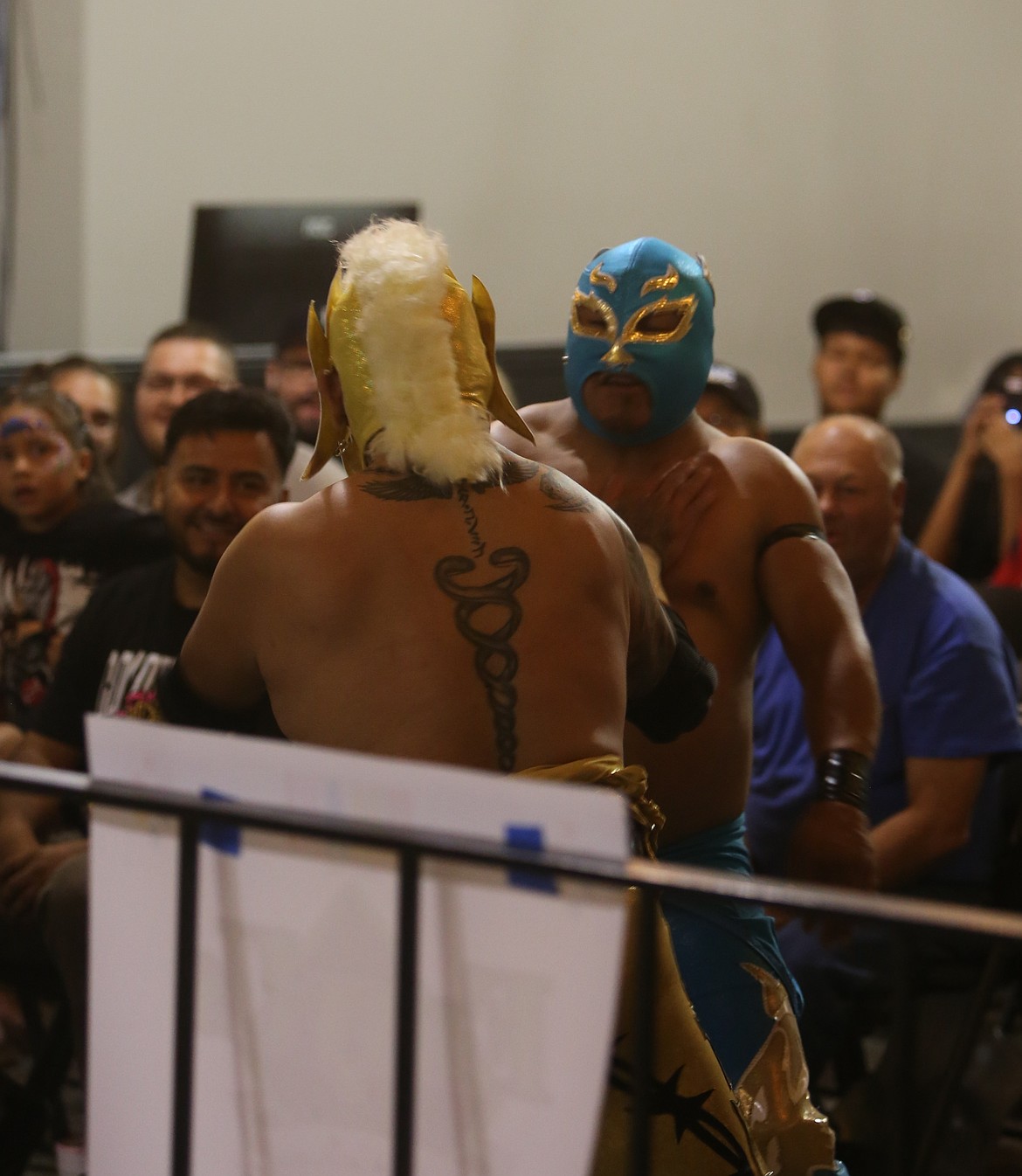 Two luchadores trade body shots in the crowd at the Lucha and Lowriders wrestling show.