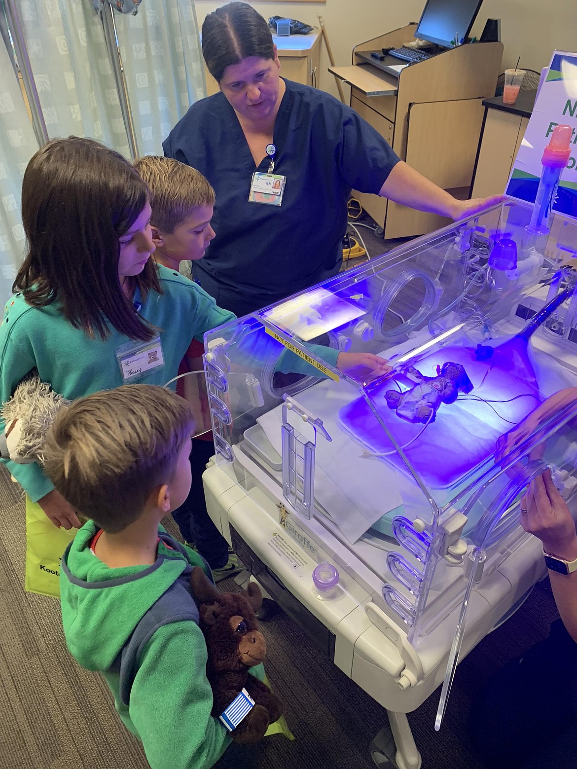 Kids crowd around a stuffed animal hooked up to hooked up to medical equipment during Kootenai Health's Teddy Bear Clinic.