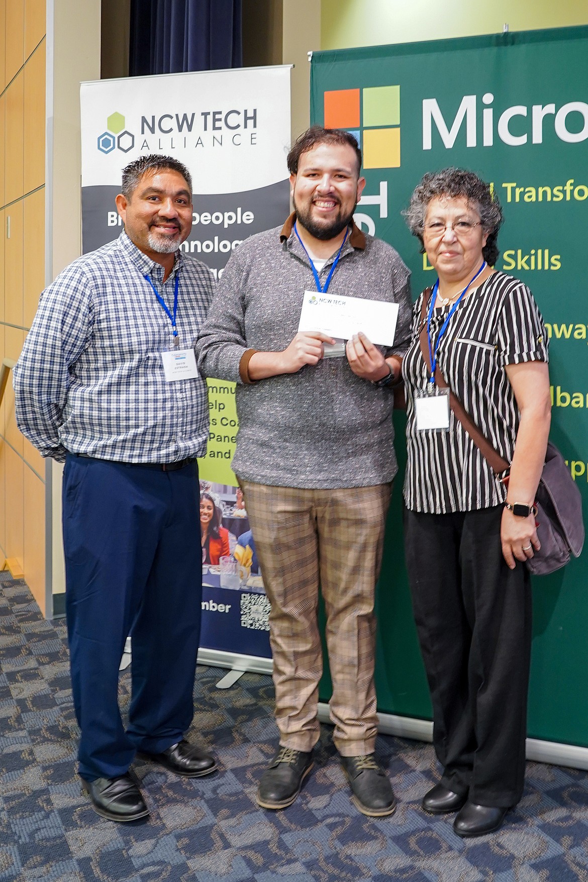 NCW Tech Alliance STEM Program manager David Estrada, left, presents a check for $1,000 to Francisco Godoy-Cortes and his mother Sandra Cortes Medina of Royal City. The mother-son team earned 35 certificates in the AI Skill-a-thon.