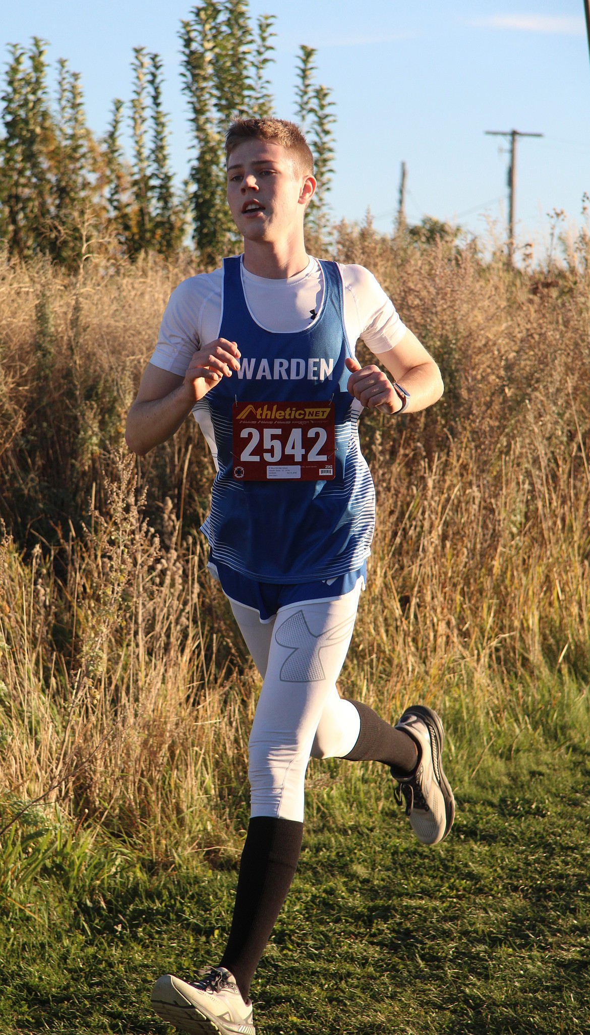 Soren Clausen with the Cougars cross country team runs past a field at Apple Ridge. Clausen finished the three-mile event with a time of 23:12.54.