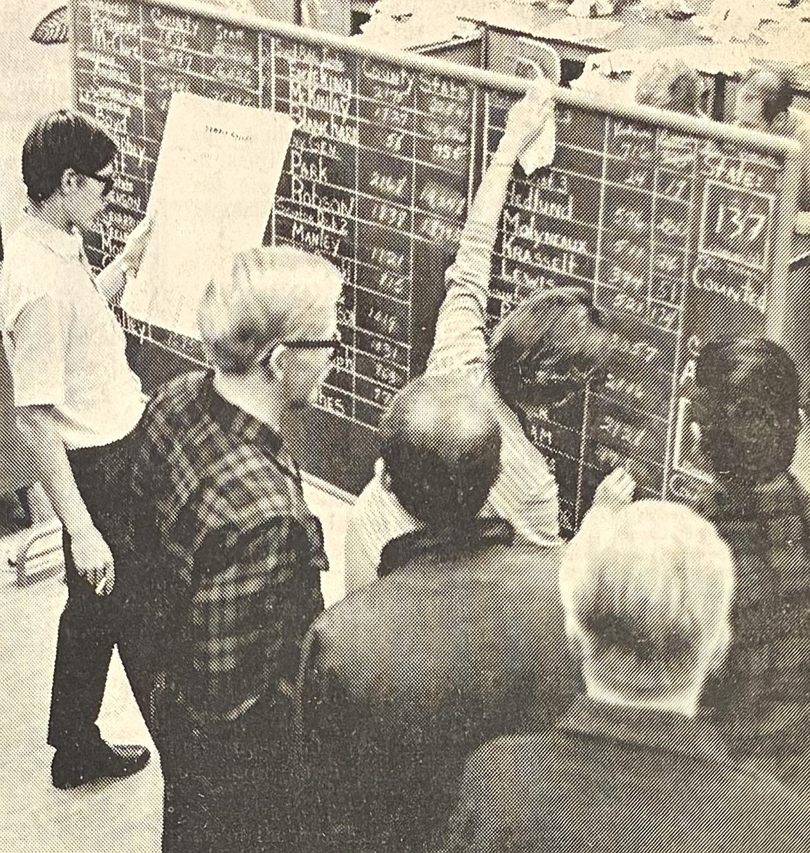 Mrs. Vernon James of KVNI-AM radio changes tallies on a chalkboard at The Press while newsman Jack Weatherford reads results in 1970.
