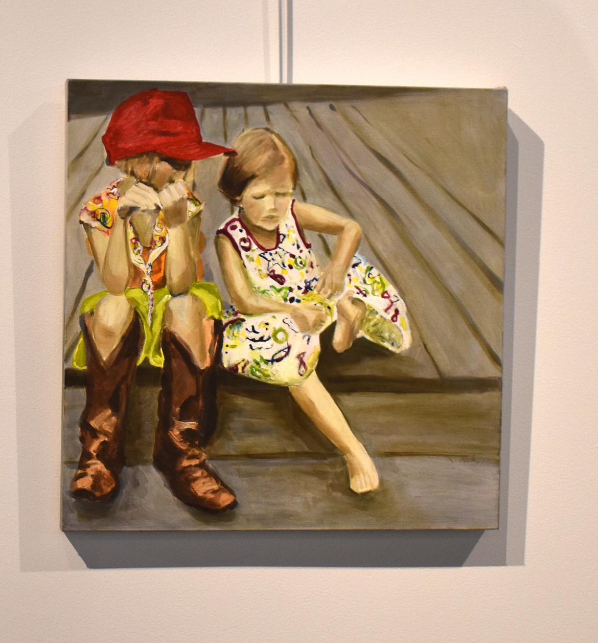 “Splinter,” an acrylic painting by Mary Rowland, shows two little girls dealing with a problem every child who’s every played outside barefoot can identify with.