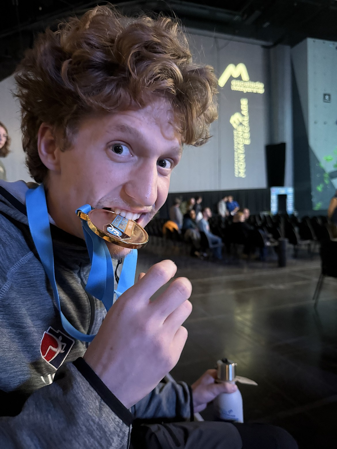 Mason Keough bites his gold medal from the International Federation of Sport Climbing Para Climbing in the World Cup competition in Laval, France.
