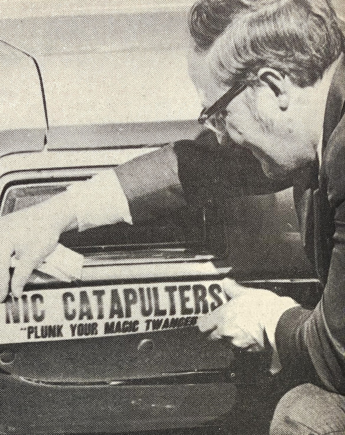 President Barry Schuler of North Idaho College places a “Plunk Your Magic Twanger” bumper sticker on his car in 1975.