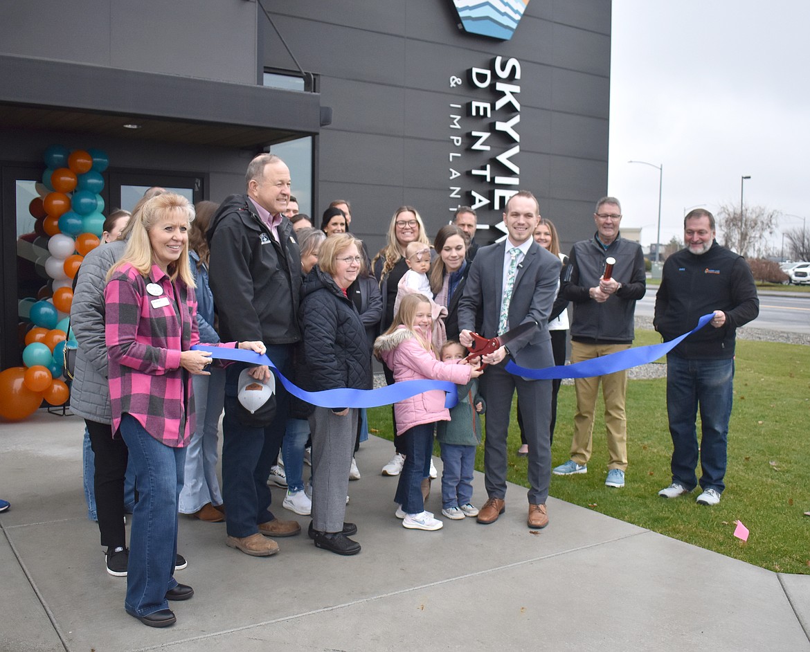 Dr. Calvin Despain, with a little help from his daughter Elsie and his son Taysom, cuts the ribbon at the new Skyview Dental Clinic Friday, surrounded by family and Moses Lake Chamber of Commerce members.