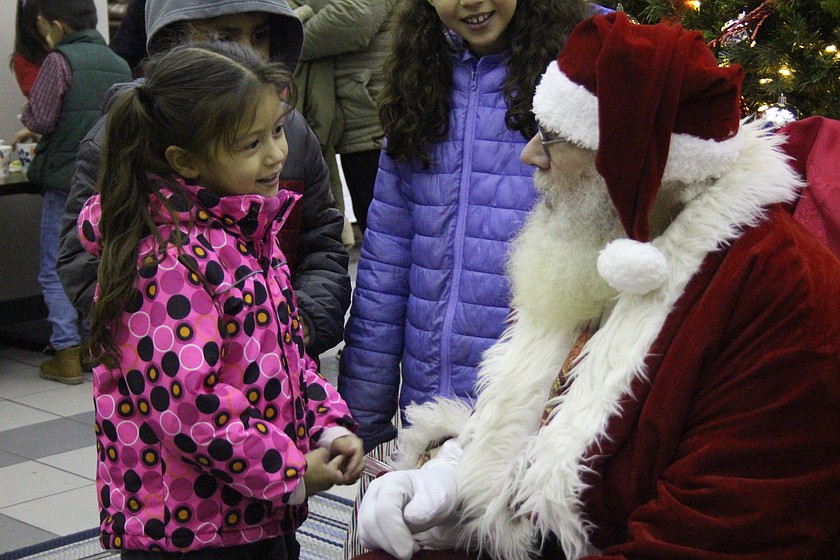 Santa (Kent Bacon) talks with a child about her Christmas wishes during the holiday celebration in Quincy Dec. 5
