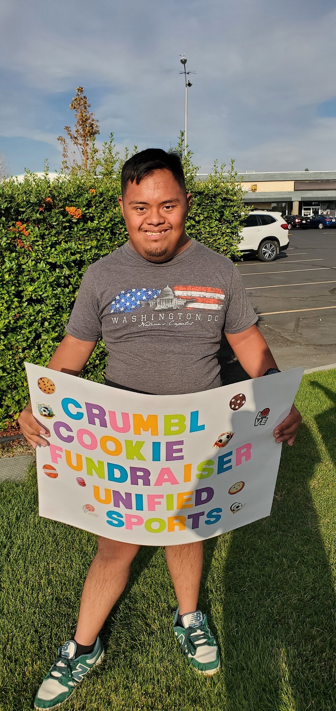 Moses Lake’s Eric Ocampo stands in a grassy patch near Crumbl Cookies during a previous fundraiser. This is the third time the Moses Lake Pals Club has collaborated with Crumbl to raise money.