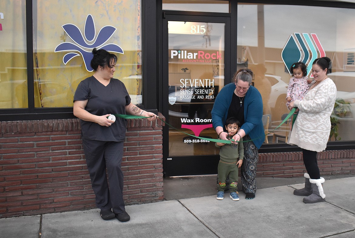 Christine Villarreal, left, and Esmeralda Sanchez, right, hold the ceremonial ribbon as Mandy Schuh helps 3-year-old Roman make the cut at the grand opening of Pillar Rock Accounting, Seventh Sense Serenity and Christine’s Waxing Room Thursday.