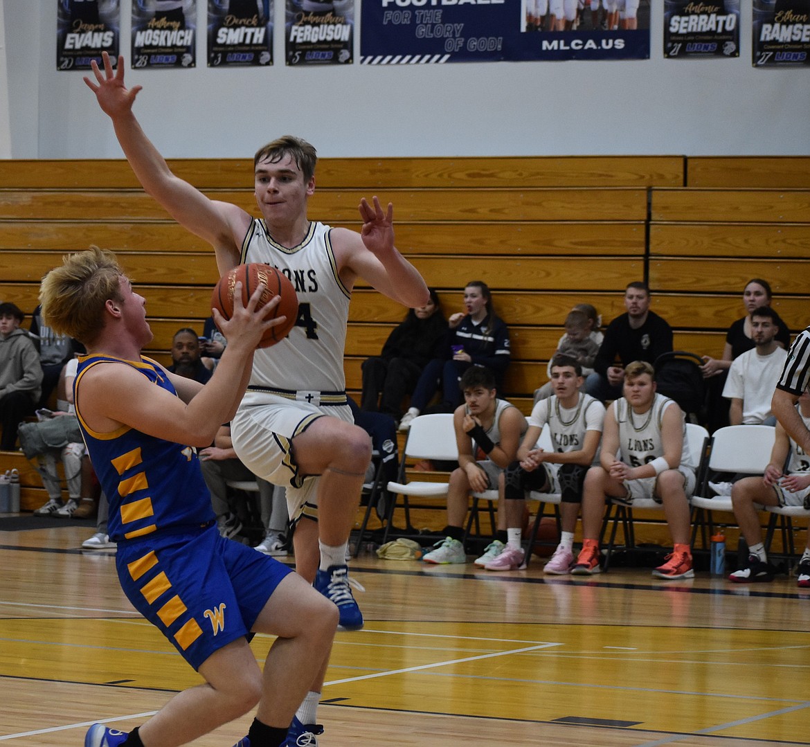 Lions senior James Robertson leaps up to block a shot from Devils player Aiden Valline during Thursday’s matchup. The two teams had a close battle to start the night, but the Lions pulled ahead quickly.
