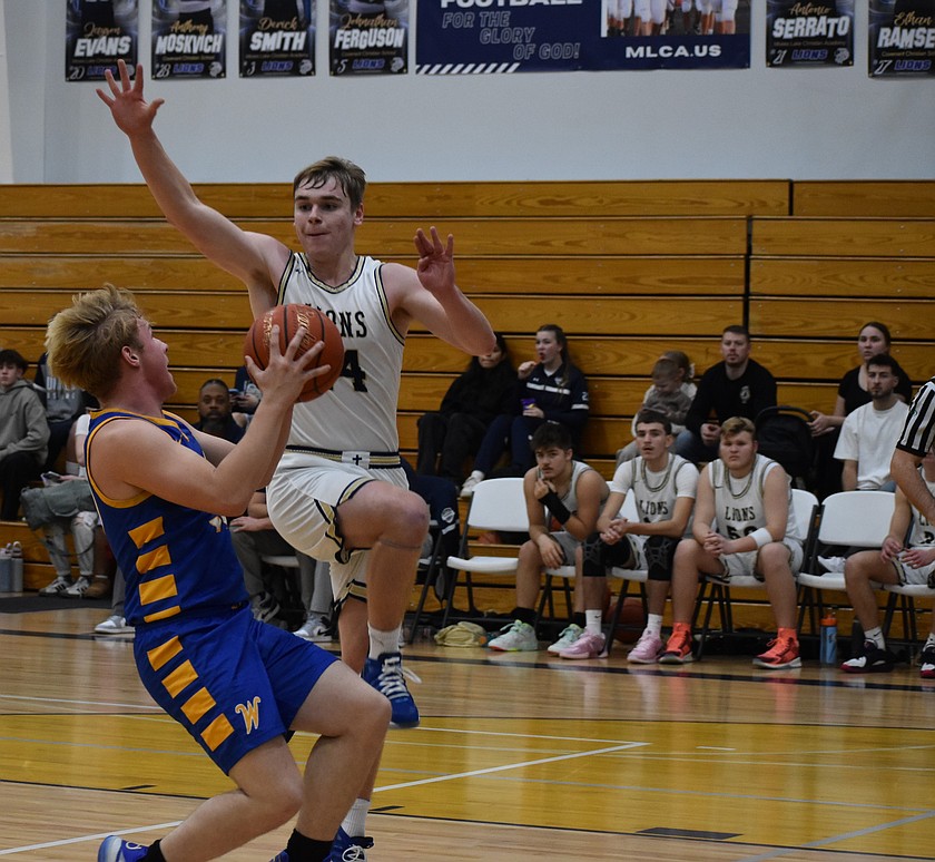 Lions senior James Robertson leaps up to block a shot from Devils player Aiden Valline during Thursday’s matchup. The two teams had a close battle to start the night, but the Lions pulled ahead quickly.