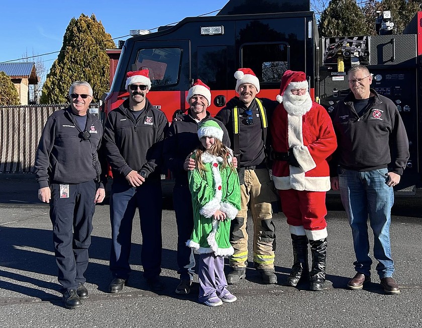 Moses Lake firefighters, with a little help from the younger generation, met the community Saturday at Ashley’s Playground with hot cocoa, Santa photos and a food drive. From left: Battalion Chief Dave Holle, Firefighter Steve Feeney, Captain Schrade Rouse, Pixie Rouse, Firefighter Paramedic Garrett Fletcher, Captain Jay Morice and Battalion Chief Joseph Schwendeman.