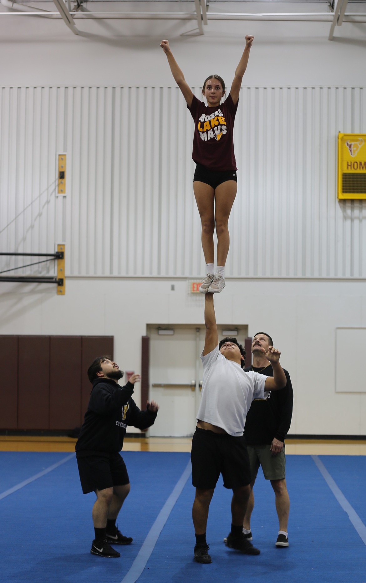 The Mavericks Assistant Coach Toby Black, back row, helps cheerleaders work through a stunt. The Mavericks routine incorporates several stunts and movements, including props like flags and signs to encourage crowd engagement.