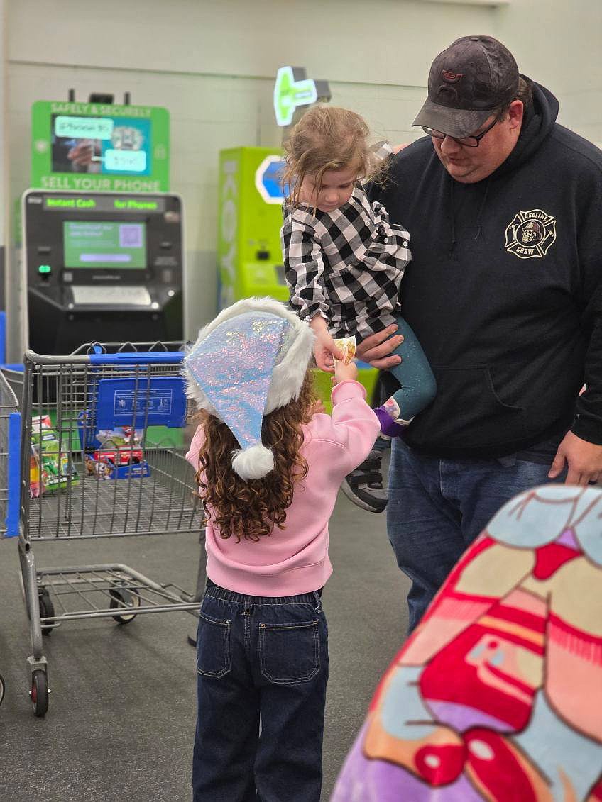 A young donor learns the joy of generosity with a donation to the Moses Lake Police Department’s Cops for Tots. Events like this give children a positive view of the police that can stay with them their whole lives, said Police Specialist Olivia Martinez.