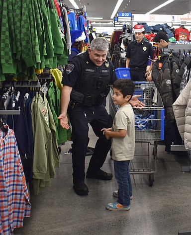 Moses Lake Police Capt. Jeff Sursely – who also serves as the department’s public information officer – checks out clothes with Angel Dominguez of Moses Lake at Shop with a Cop Tuesday.