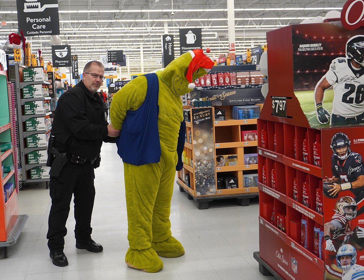 Soap Lake Police Chief Patrick Canady slaps the cuffs on the Grinch at the Shop with a Cop event in Ephrata Dec. 11.