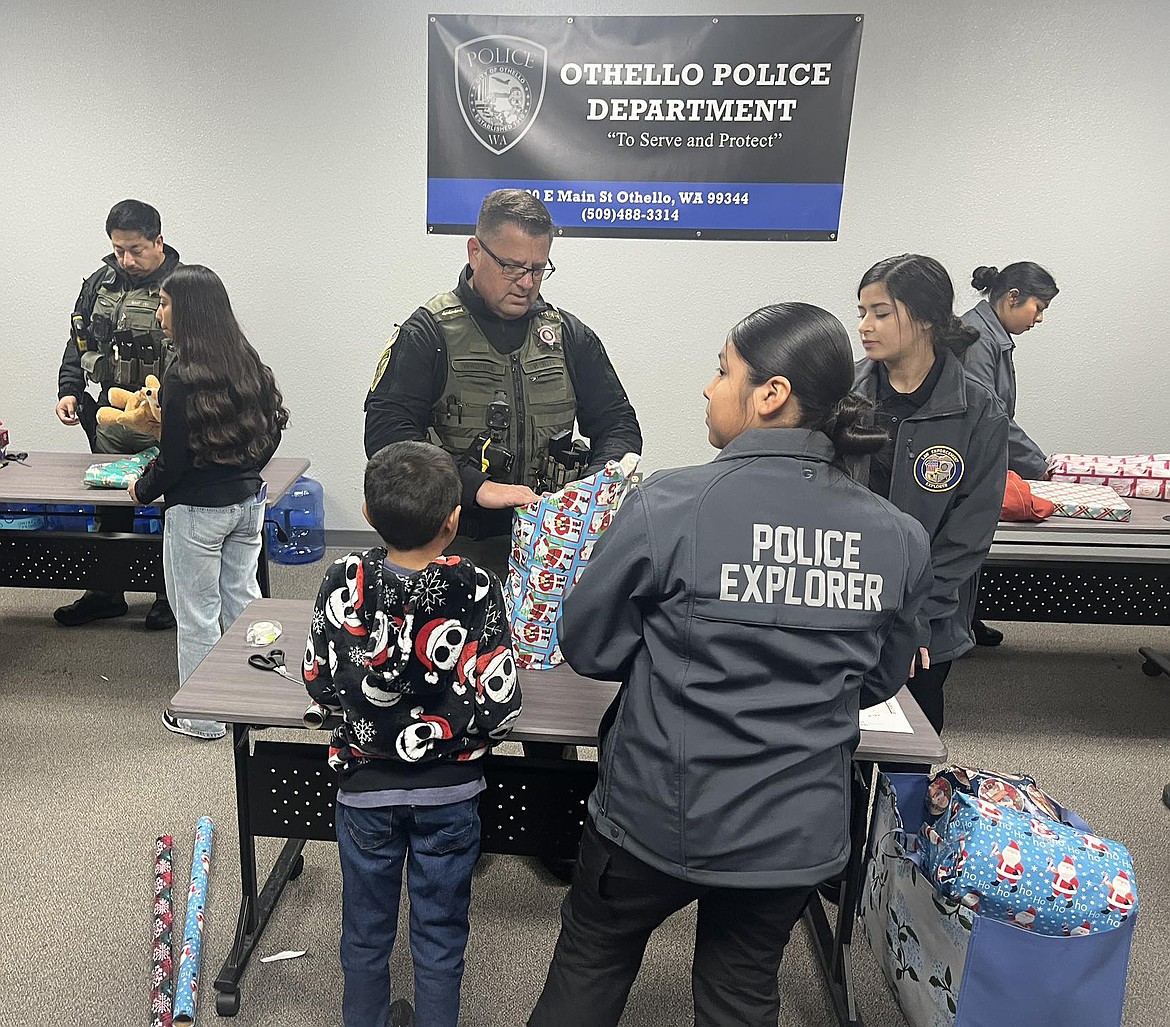 Adams County Sheriff Dale Wagner helps Othello Police Explorers wrap gifts at Othello’s Shop with a Cop Dec. 13.