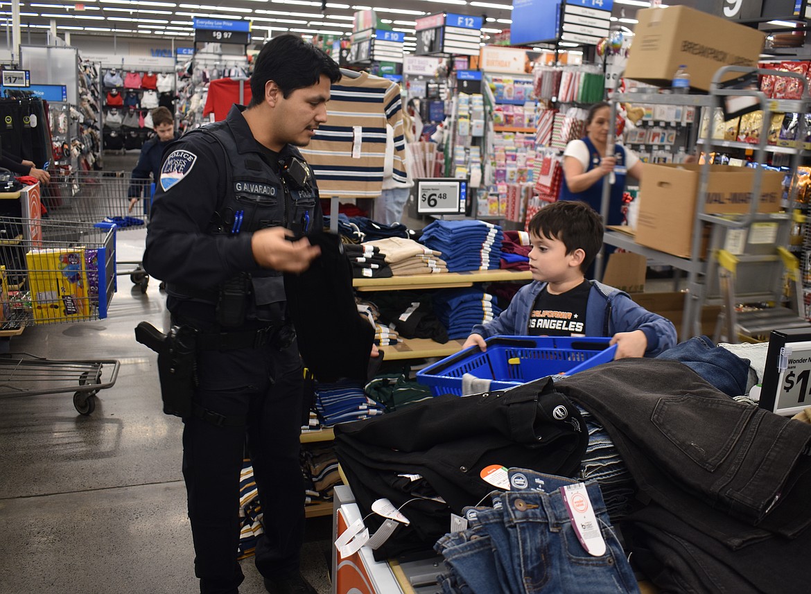 Moses Lake Police Officer Gregorio Alvarado picks out clothes with 8-year-old Carter Dominguez.