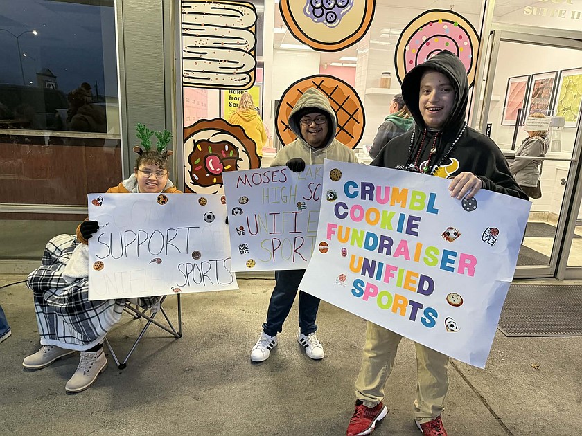 Josline Dominguez-Gomez, Eric Ocampo and DJ Parker hold up signs for the Pals Club’s unified sports fundraiser on Thursday. Mavs Assistant Coach Sarah White said the team had about four players who were able to attend the fundraiser.