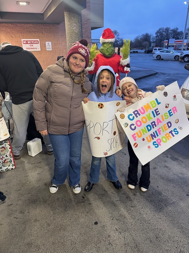 Mavs Assistant Coach Sarah White’s daughter and two friends hold up signs to help support the unified sports fundraiser. White said she was pleasantly surprised by the number of people she went to high school with who came with their own children to come support the Pals Club.